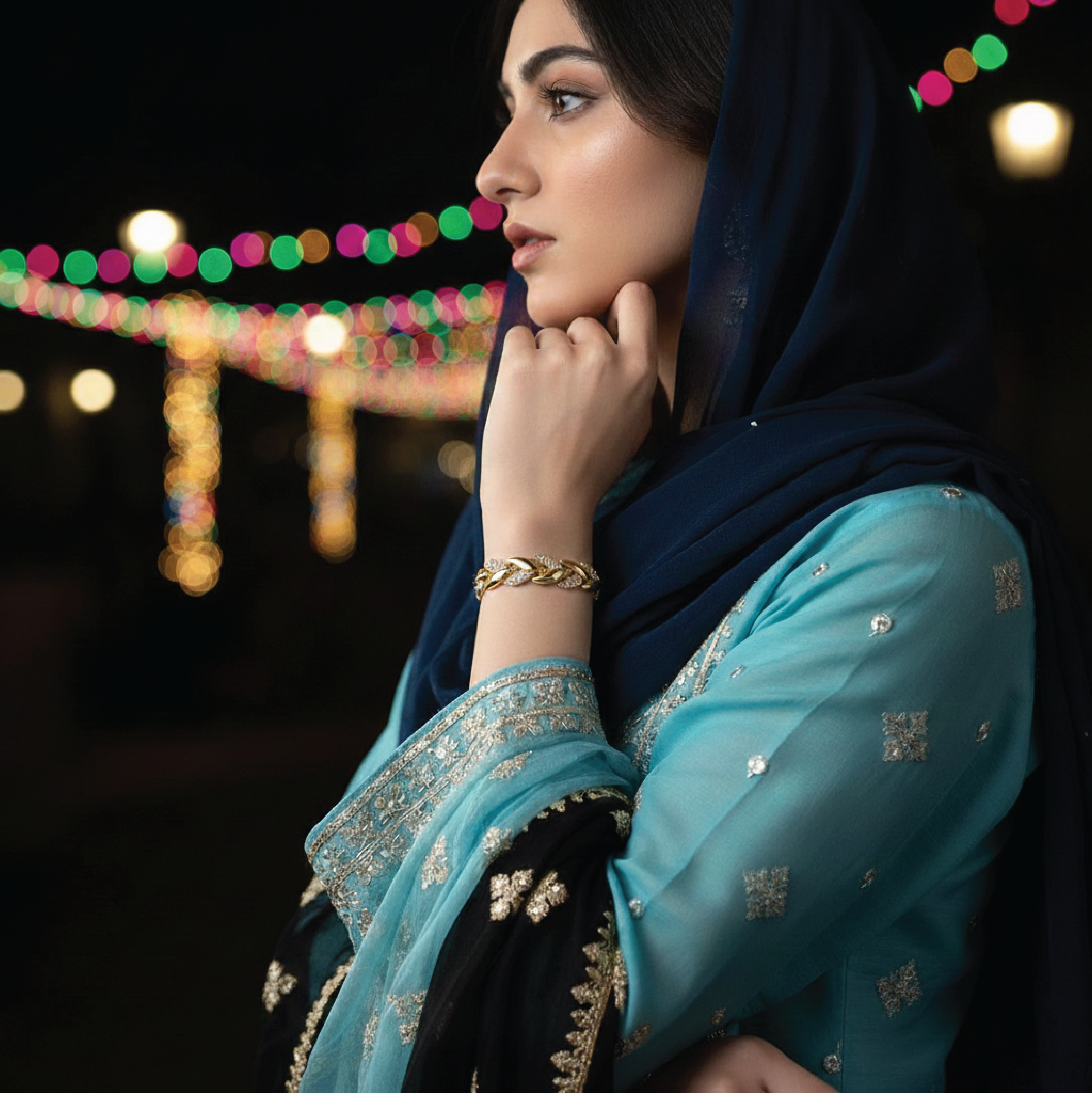 Model wearing a gold-tone chain bracelet with an aqua outfit